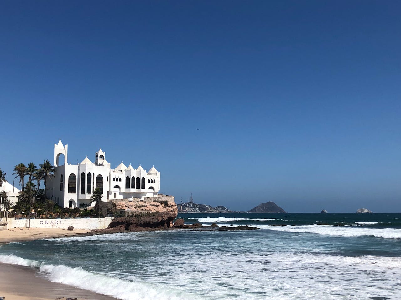 Captivating view of a beachfront building in Mazatlán, Sinaloa with clear skies and ocean waves.